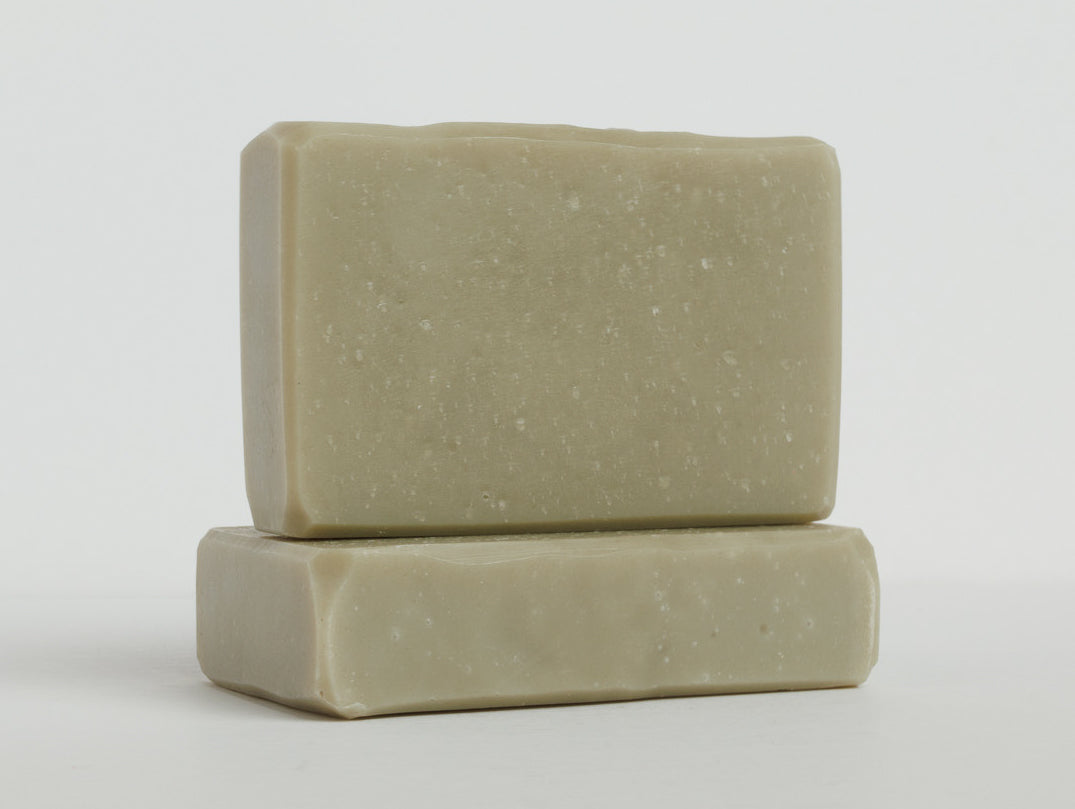 Two mint green bars of soap are stacked on a clean white surface with one bar lying flat and the other placed upright on top. The soaps have a smooth texture and rectangular shape with slightly rounded edges.