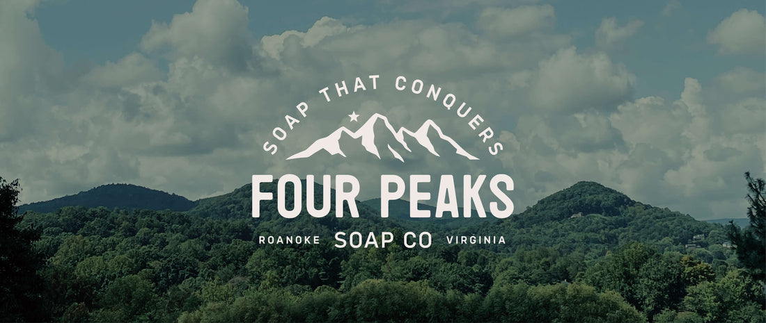 Logo for Four Peaks Soap Co featuring mountain peaks and the tagline "Soap That Conquers," with a scenic background of green hills and cloudy sky. Located in Roanoke, Virginia.